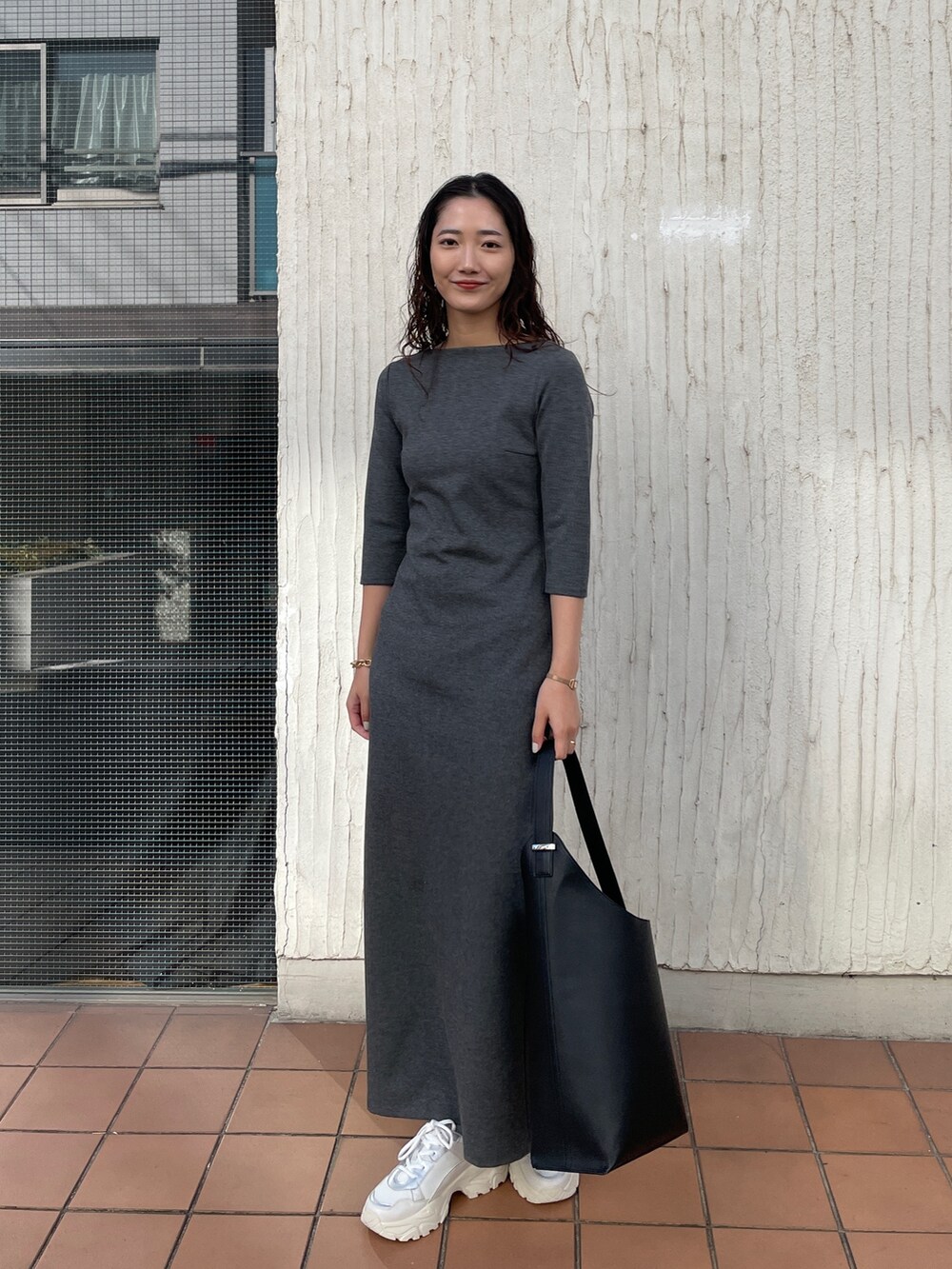 ブラック系のショルダーバッグ、グレー系のワンピース、ホワイト系のスニーカーを着用したレディースの冬コーディネートの4枚目の写真