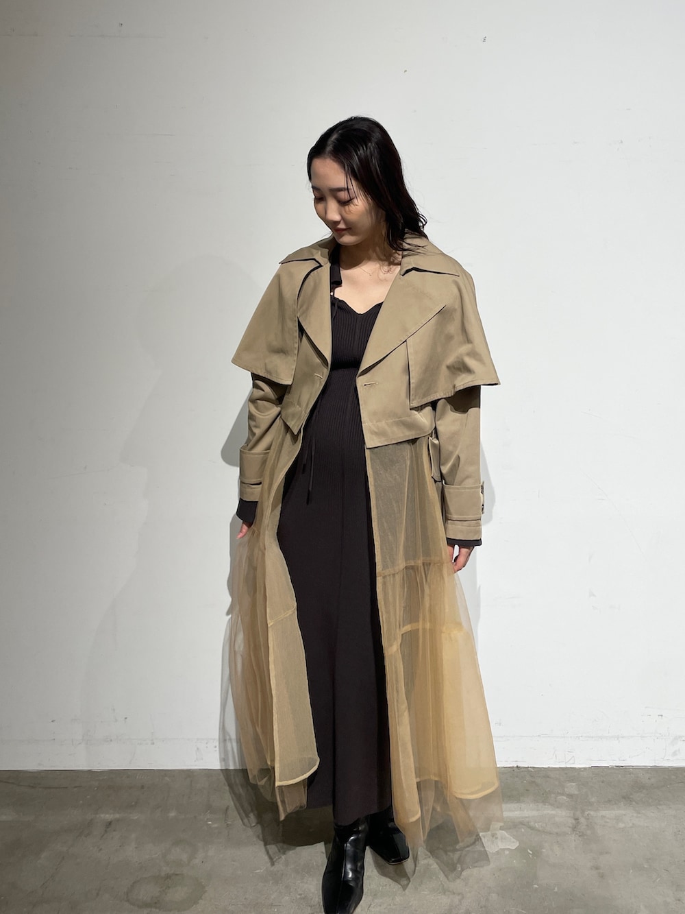 ブラック系のブーツ、グレー系のワンピース、ベージュ系のトレンチコートを着用したレディースの春コーディネートの5枚目の写真