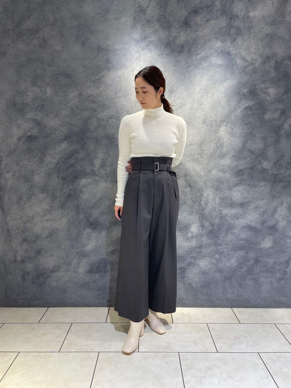 グレー系のその他パンツ、ホワイト系のニット/セーター、ホワイト系のブーツを着用したレディースの冬コーディネートの3枚目の写真