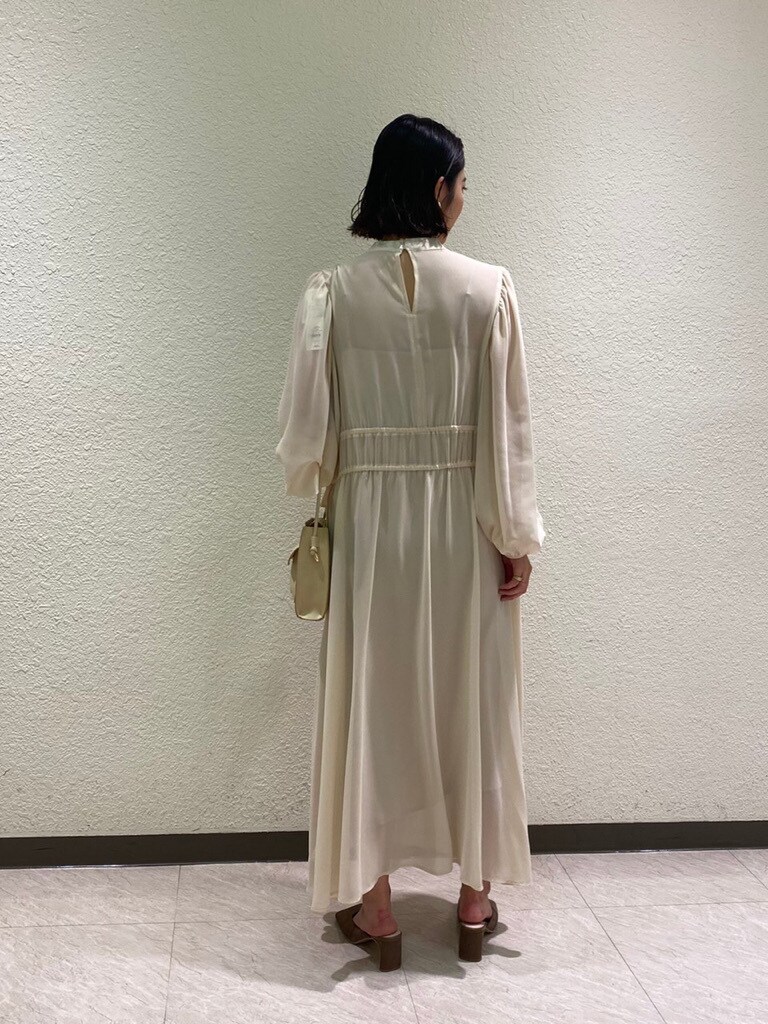 ベージュ系のハンドバッグ、ベージュ系のサンダル、ホワイト系のワンピースを着用したレディースの冬コーディネートの4枚目の写真