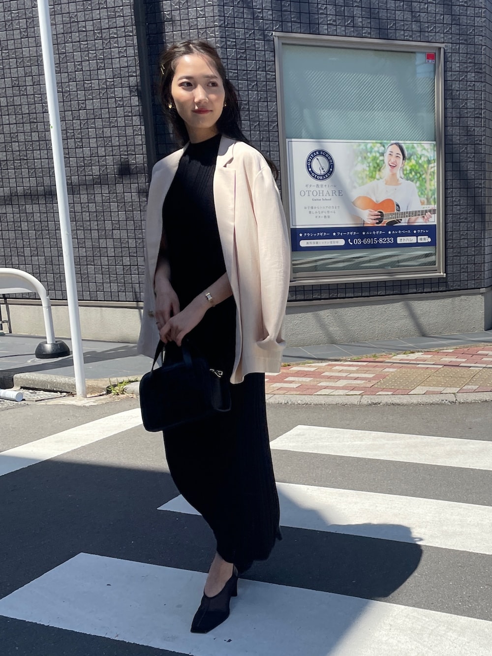 ブラック系のショルダーバッグ、ブラック系のワンピース、ベージュ系のテーラードジャケットを着用したレディースの春コーディネートの4枚目の写真