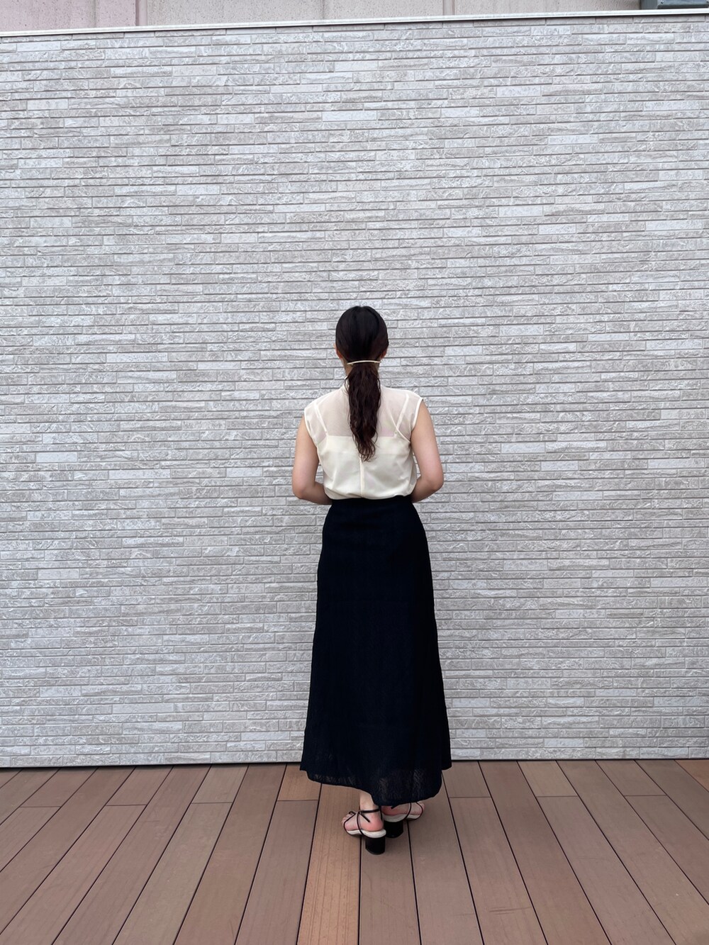 ブラック系のスカート、ホワイト系のTシャツ/カットソー、ブラック系のサンダルを着用したレディースの夏コーディネートの5枚目の写真