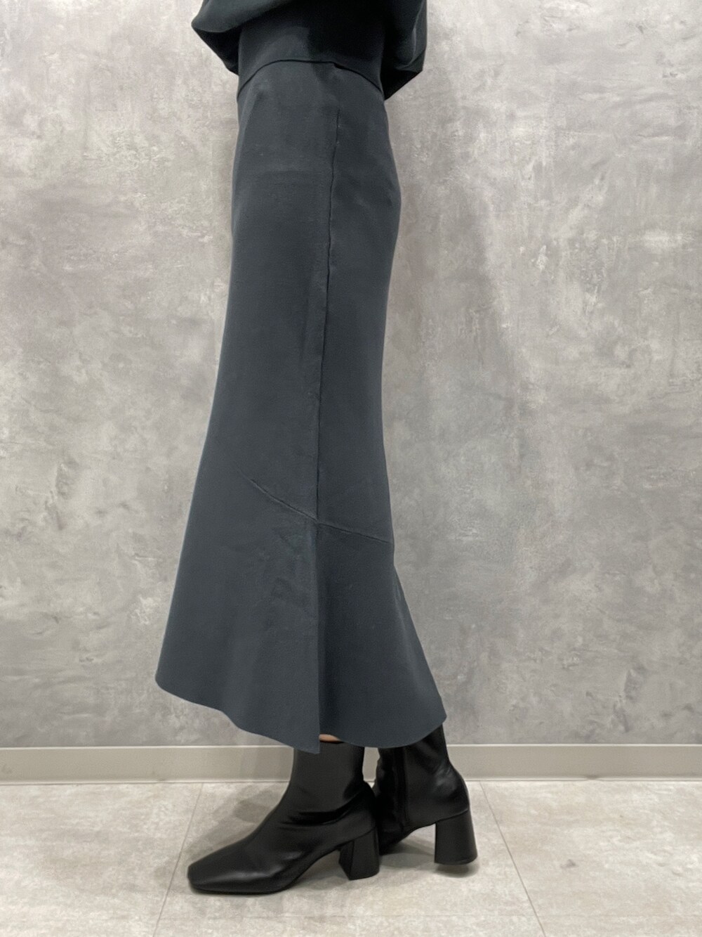 ホワイト系のカーディガン/ボレロ、ブラック系のブーツ、グリーン系のスカートを着用したレディースの冬コーディネートの10枚目の写真