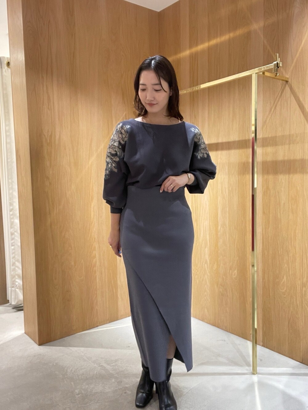 グレー系のスカート、グレー系のニット/セーター、ブラック系のブーツを着用したレディースの秋コーディネートの3枚目の写真