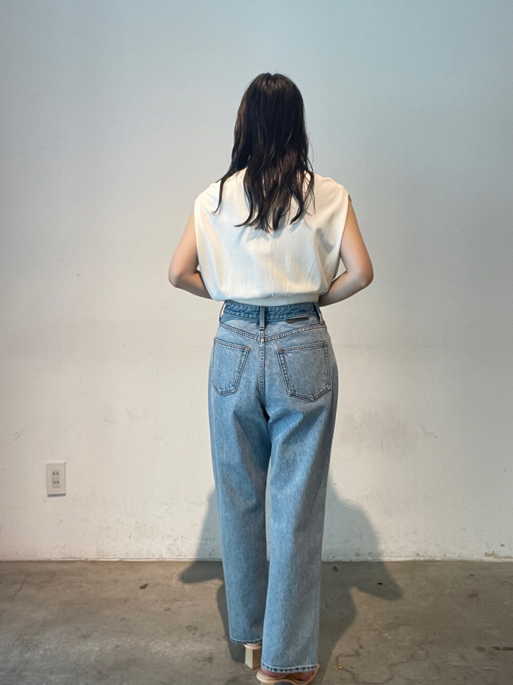 ブルー系のデニムパンツ、ホワイト系のニット/セーター、イエロー系のサンダルを着用したレディースの夏コーディネートの6枚目の写真