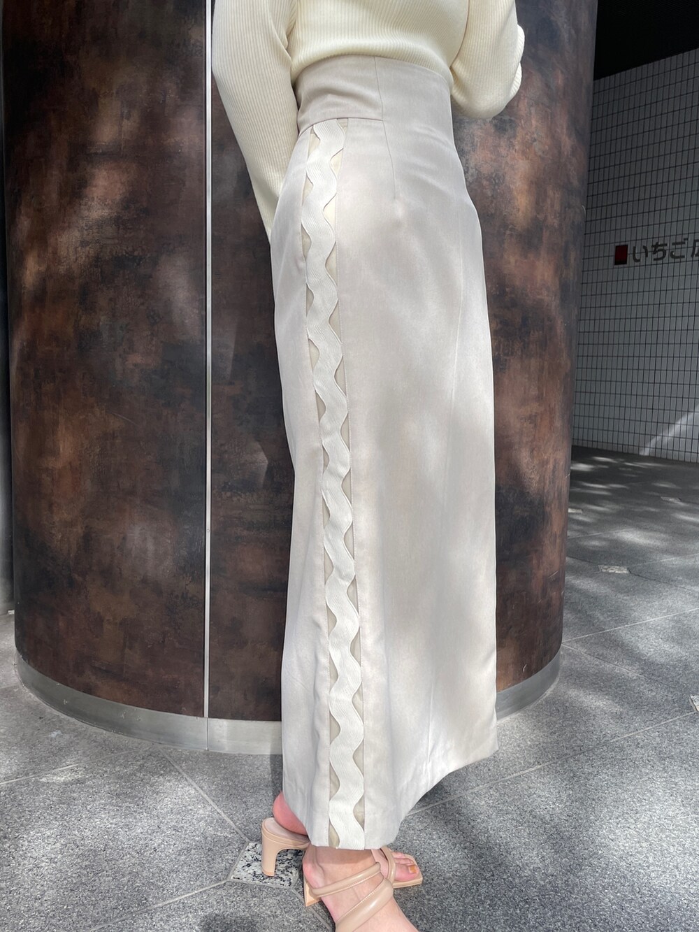 ベージュ系のサンダル、ベージュ系のスカート、ホワイト系のニット/セーターを着用したレディースの冬コーディネートの9枚目の写真