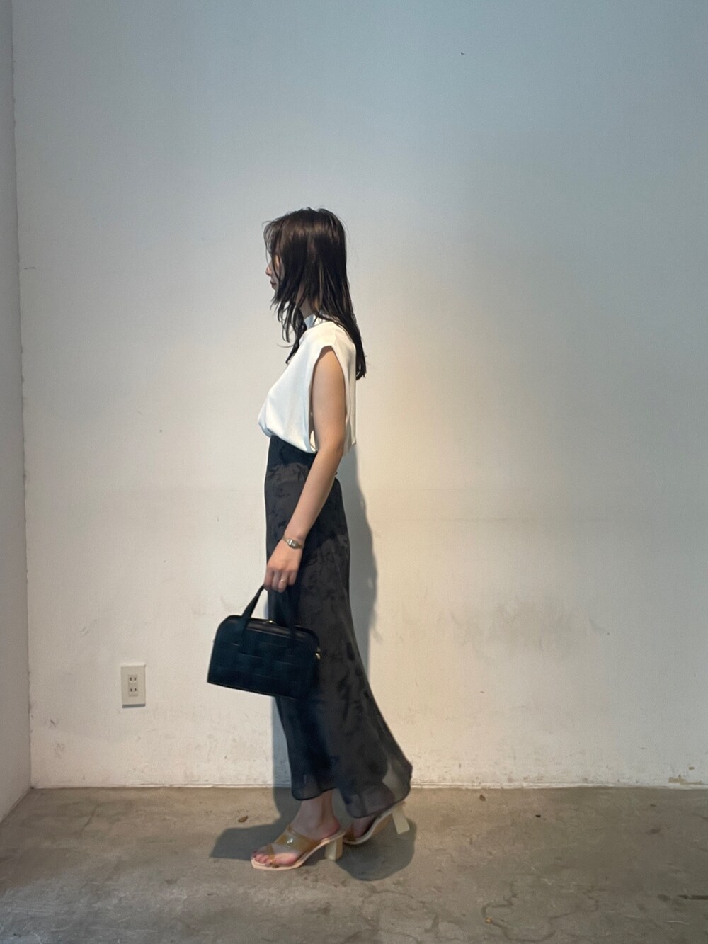 ホワイト系のニット/セーター、ブラック系のショルダーバッグ、イエロー系のサンダルを着用したレディースの夏コーディネートの5枚目の写真
