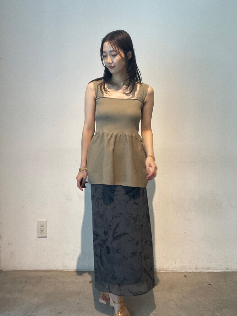 グレー系のスカート、イエロー系のサンダル、ベージュ系のニット/セーターを着用したレディースの夏コーディネートの2枚目の写真