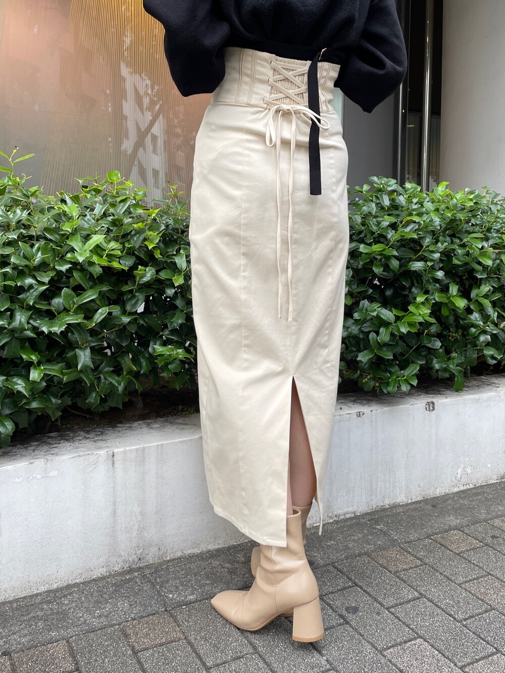 ベージュ系のブーツ、ブラック系のニット/セーター、ホワイト系のスカートを着用したレディースの秋コーディネートの7枚目の写真