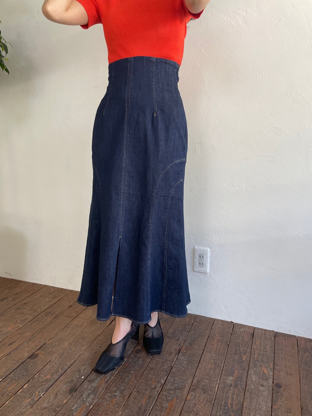 オレンジ系のニット/セーター、ブルー系のデニムスカート、ブラック系のパンプスを着用したレディースの春コーディネートの7枚目の写真