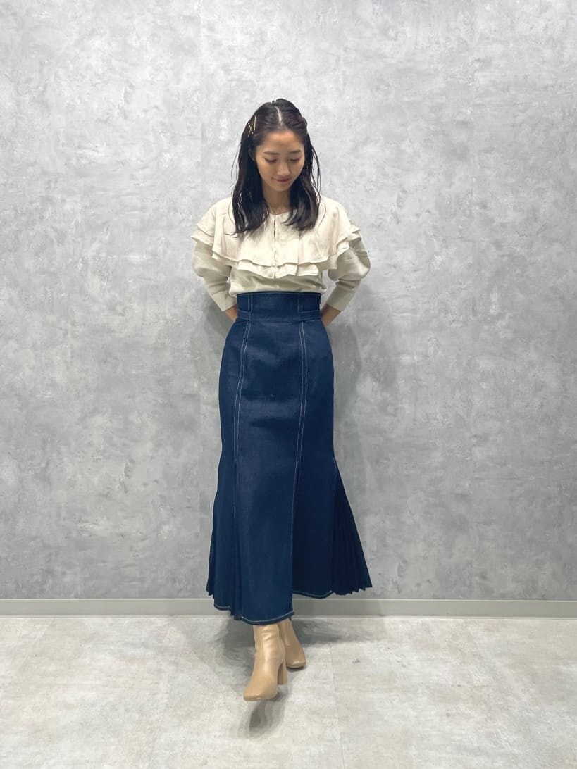 ベージュ系のブーツ、ブルー系のスカート、ホワイト系のニット/セーターを着用したレディースの秋コーディネートの3枚目の写真