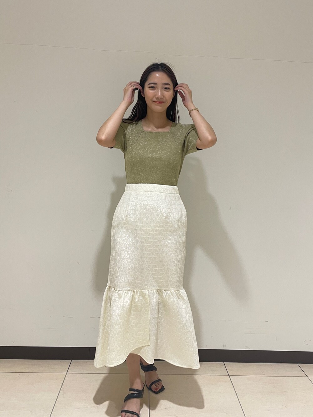 ホワイト系のスカート、グリーン系のニット/セーター、ブラック系のサンダルを着用したレディースの春コーディネートの2枚目の写真