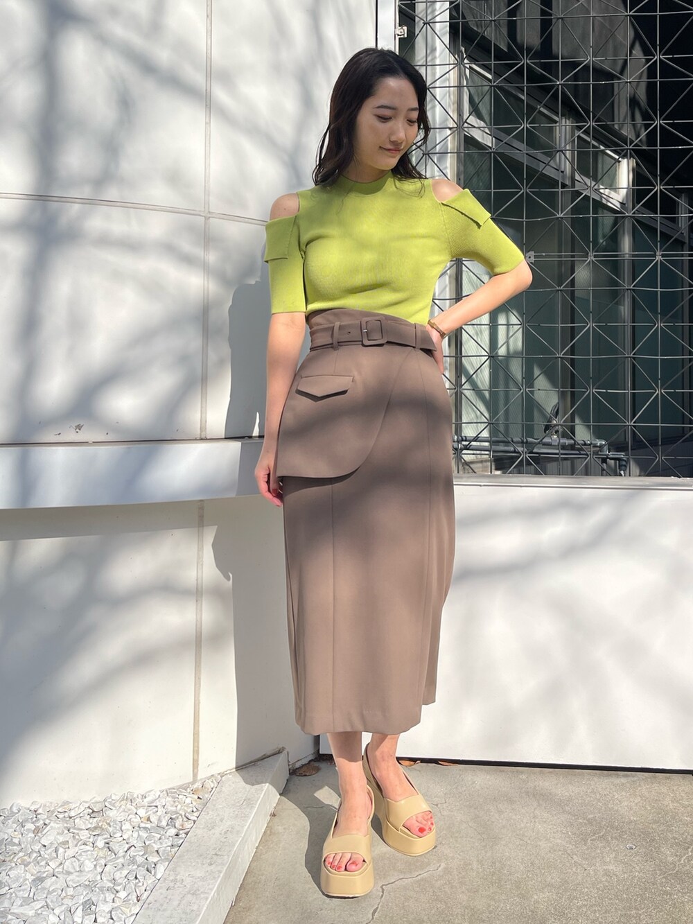 グリーン系のニット/セーター、ブラウン系のスカート、ベージュ系のサンダルを着用したレディースの冬コーディネートの2枚目の写真