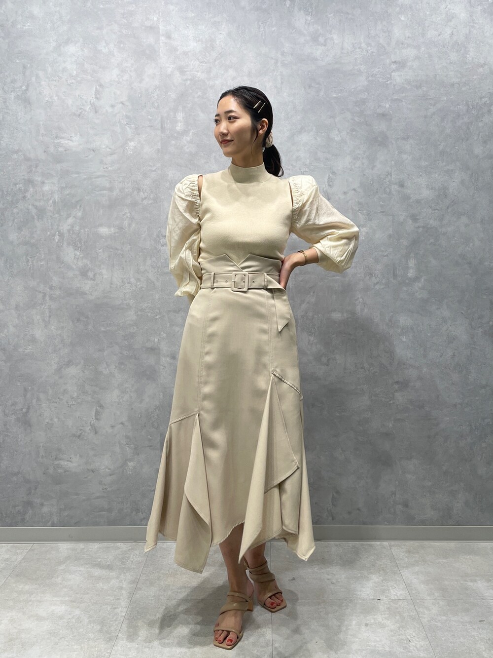 ベージュ系のサンダル、ホワイト系のニット/セーター、ホワイト系のスカートを着用したレディースの冬コーディネートの2枚目の写真