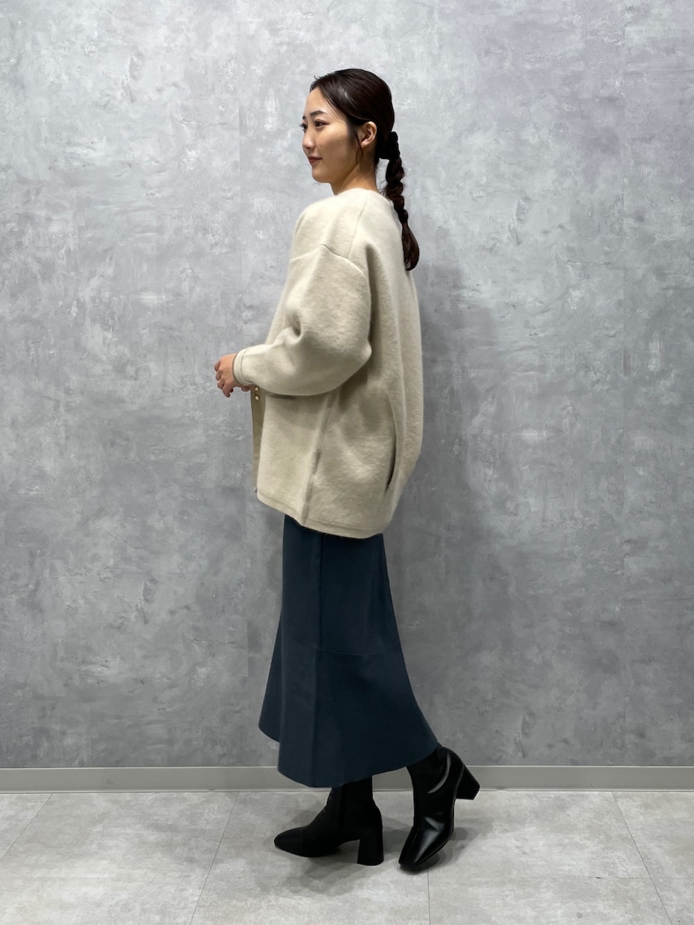 ホワイト系のカーディガン/ボレロ、ブラック系のブーツ、グリーン系のスカートを着用したレディースの冬コーディネートの2枚目の写真