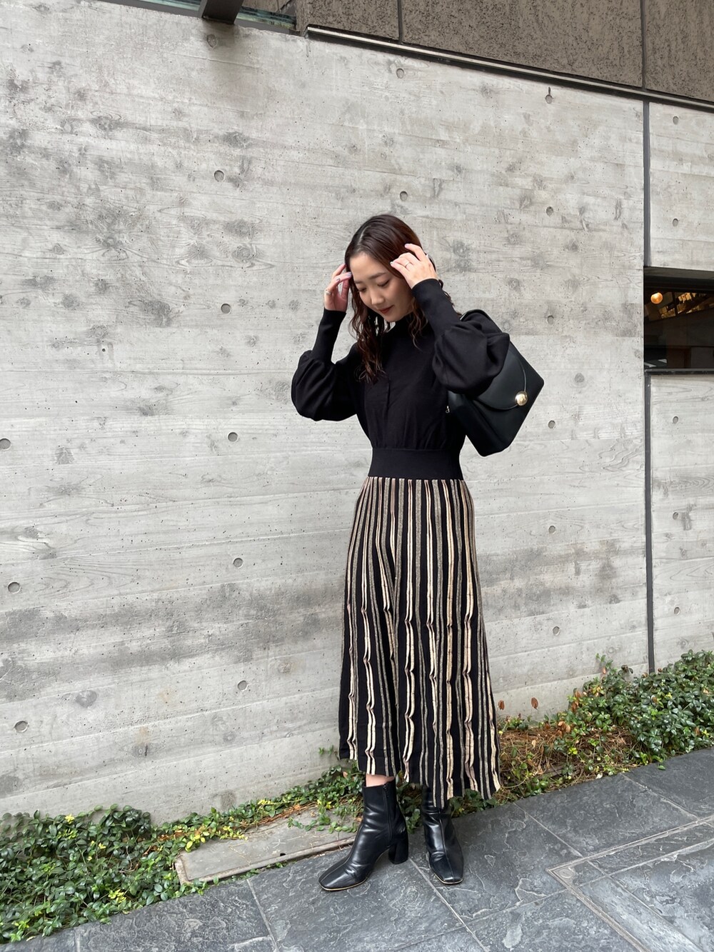 ブルー系のノーカラーコート、ブラック系のワンピース、ブラック系のブーツを着用したレディースの冬コーディネートの6枚目の写真