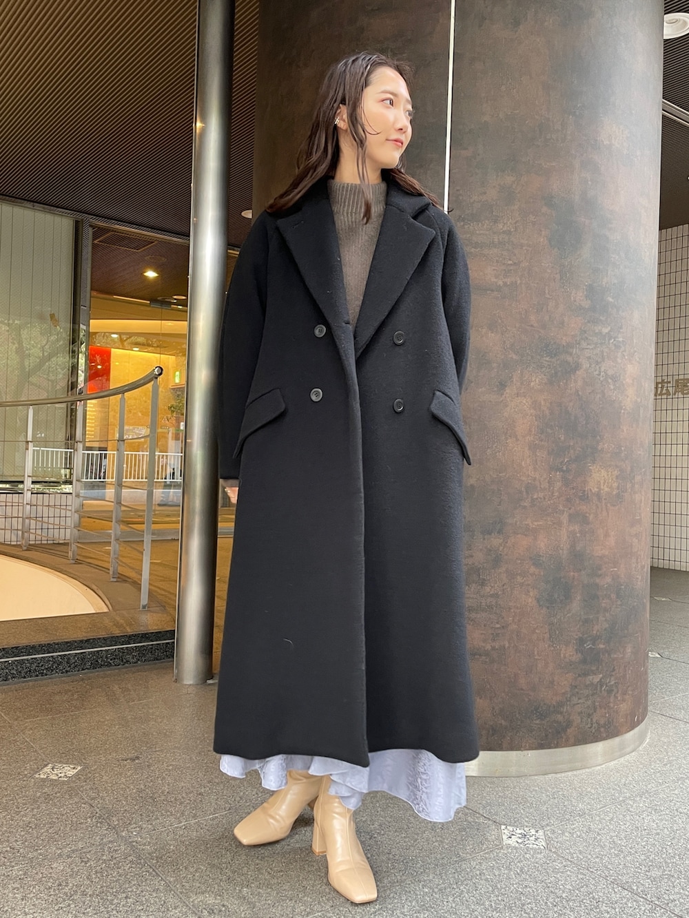 ベージュ系のニット/セーター、ベージュ系のブーツ、ブラック系のその他アウターを着用したレディースの冬コーディネートの2枚目の写真