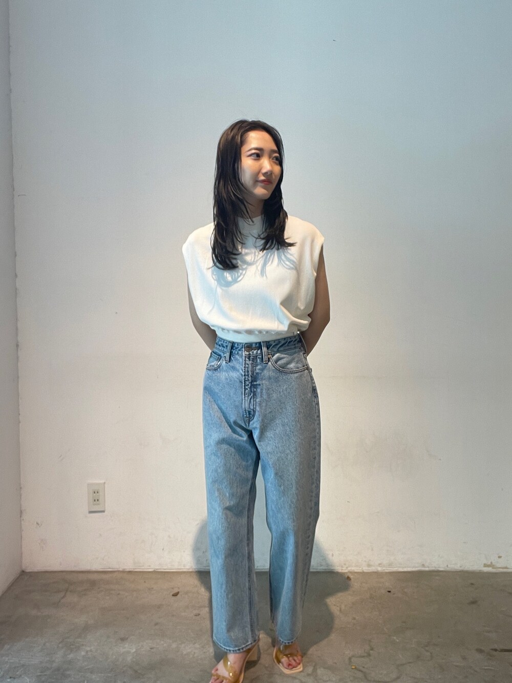 ブルー系のデニムパンツ、ホワイト系のニット/セーター、イエロー系のサンダルを着用したレディースの夏コーディネートの2枚目の写真