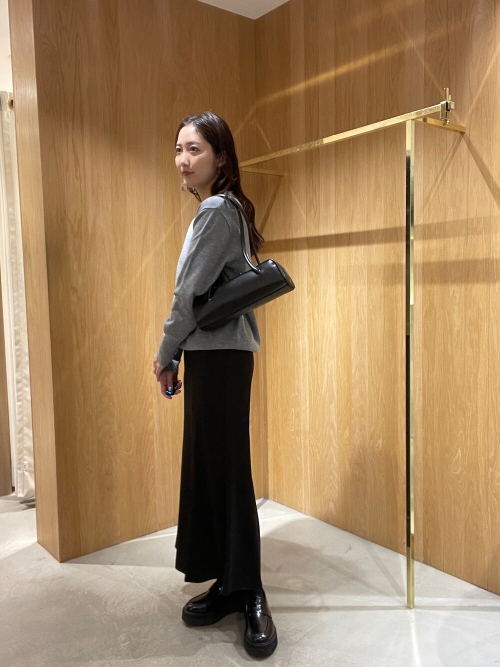 グレー系のニット/セーター、ブラック系のスカート、ブラック系のローファーを着用したレディースの秋コーディネートの3枚目の写真