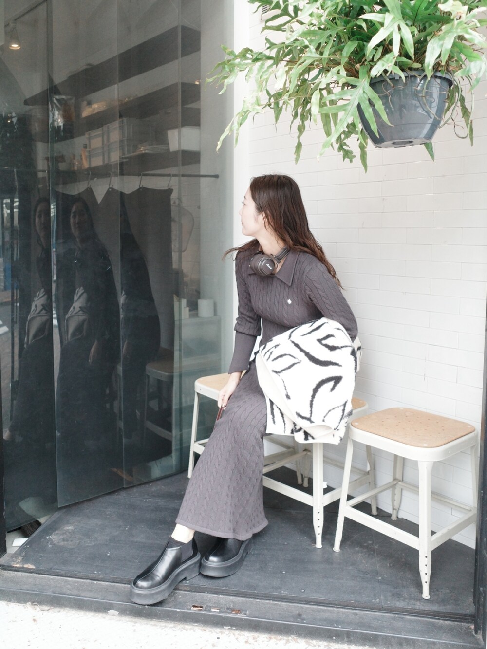 グレー系のワンピース、ホワイト系のブルゾン、ブラック系のブーツを着用したレディースの夏コーディネートの2枚目の写真