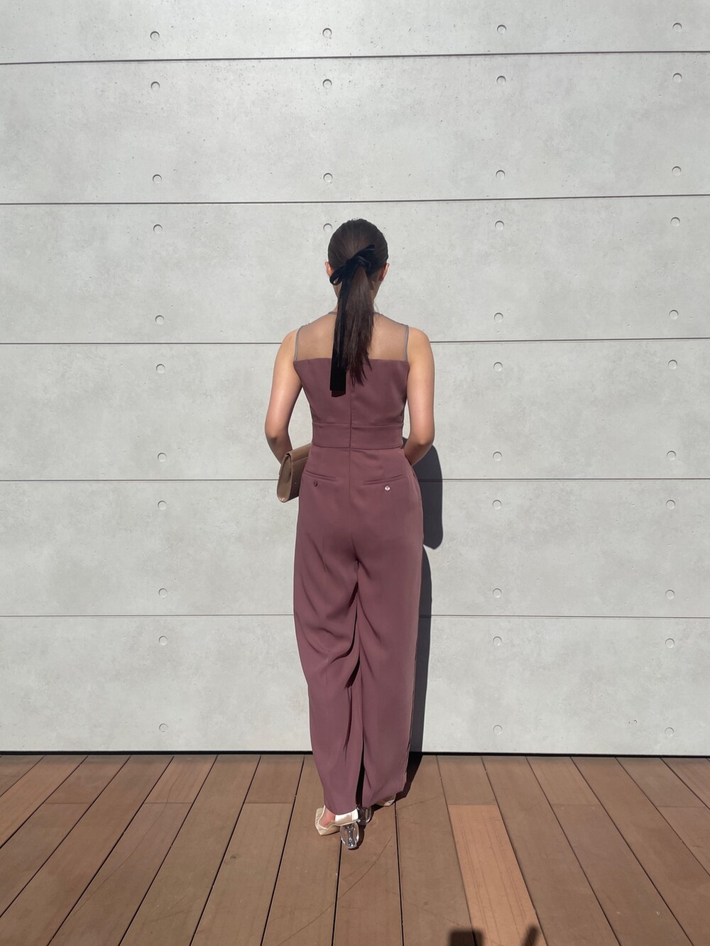 ピンク系のパンツドレス、ゴールド系のハンドバッグ、ベージュ系のパンプスを着用したレディースの秋コーディネートの6枚目の写真