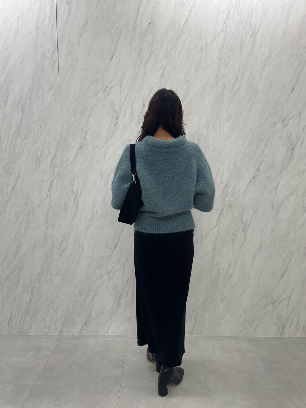 グリーン系のニット/セーター、ブラック系のブーツ、ブラック系のスカートを着用したレディースの冬コーディネートの5枚目の写真