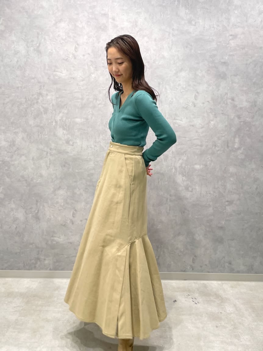 ベージュ系のスカート、ベージュ系のブーツ、グリーン系のニット/セーターを着用したレディースの夏コーディネートの4枚目の写真