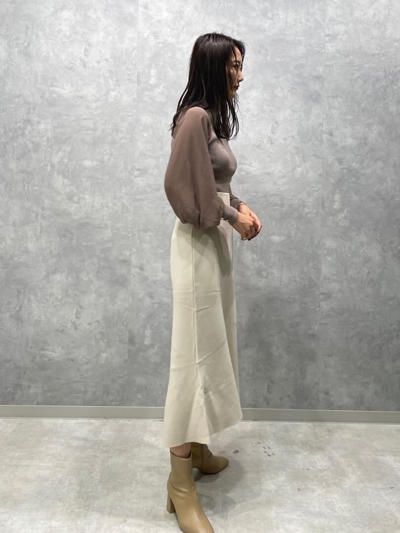 ベージュ系のブーツ、ベージュ系のニット/セーター、ホワイト系のスカートを着用したレディースの秋コーディネートの3枚目の写真