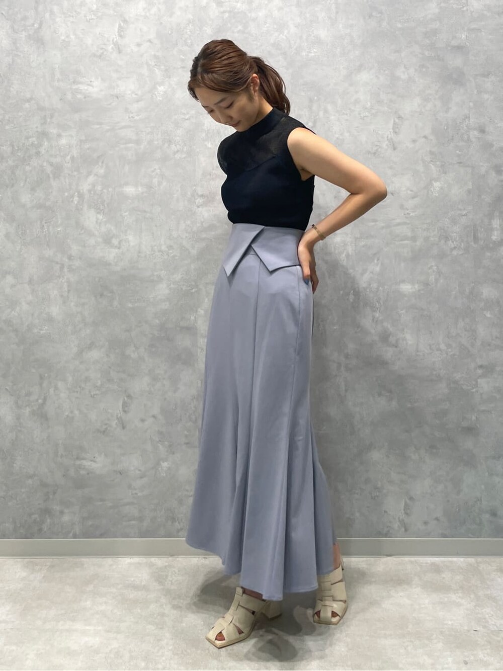 ホワイト系のサンダル、ブラック系のニット/セーター、ブルー系のスカートを着用したレディースの夏コーディネートの2枚目の写真