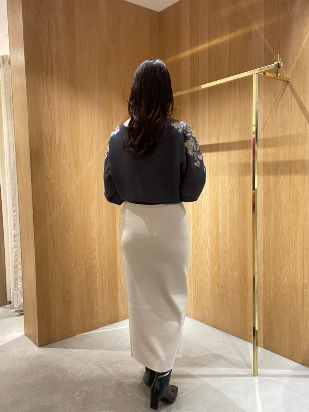 ホワイト系のスカート、グレー系のニット/セーター、ブラック系のブーツを着用したレディースの秋コーディネートの4枚目の写真