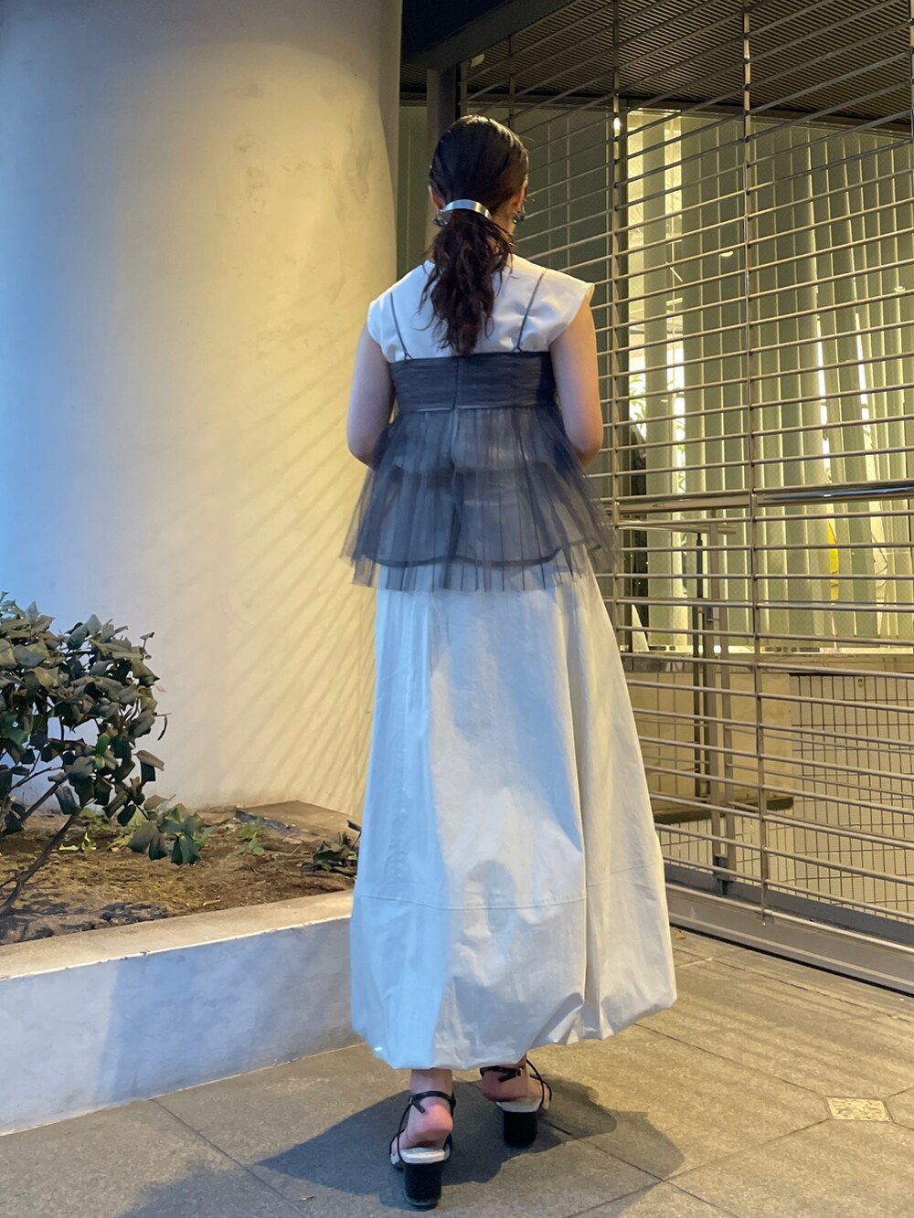 グレー系のTシャツ/カットソー、ホワイト系のスカート、ブラック系のサンダルを着用したレディースの春コーディネートの6枚目の写真