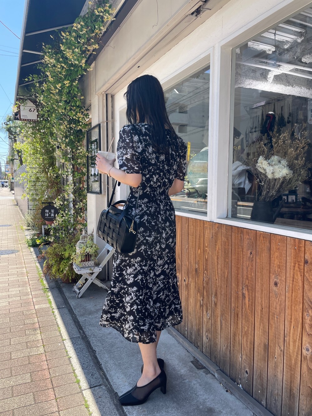 ブラック系のショルダーバッグ、ブラック系のワンピース、ブラック系のパンプスを着用したレディースの春コーディネートの2枚目の写真