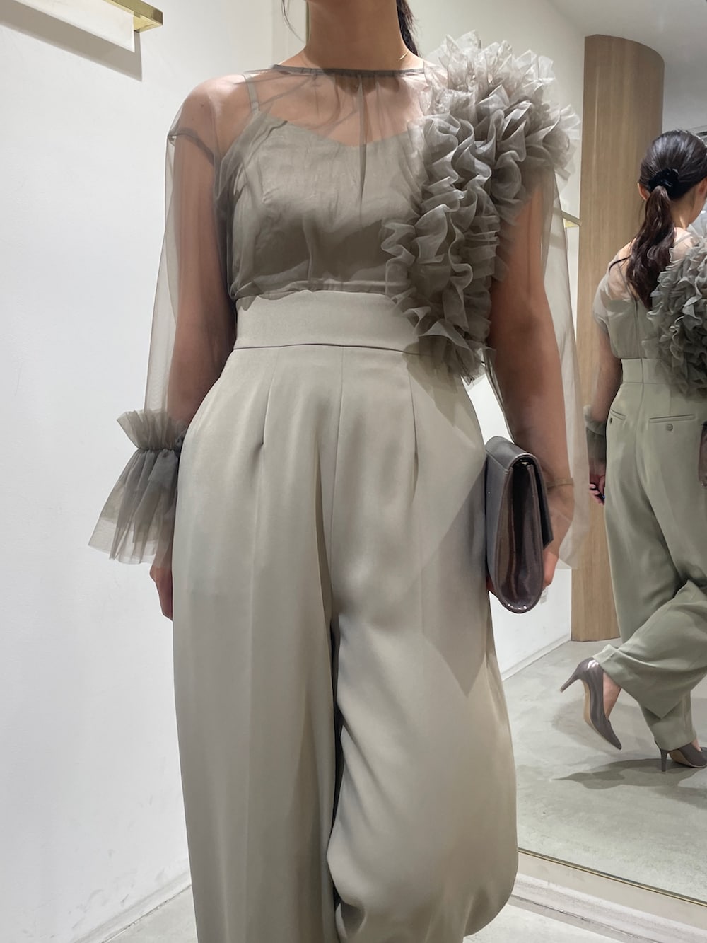 グリーン系のパンツドレス、シルバー系のハンドバッグ、シルバー系のパンプスを着用したレディースの冬コーディネートの7枚目の写真