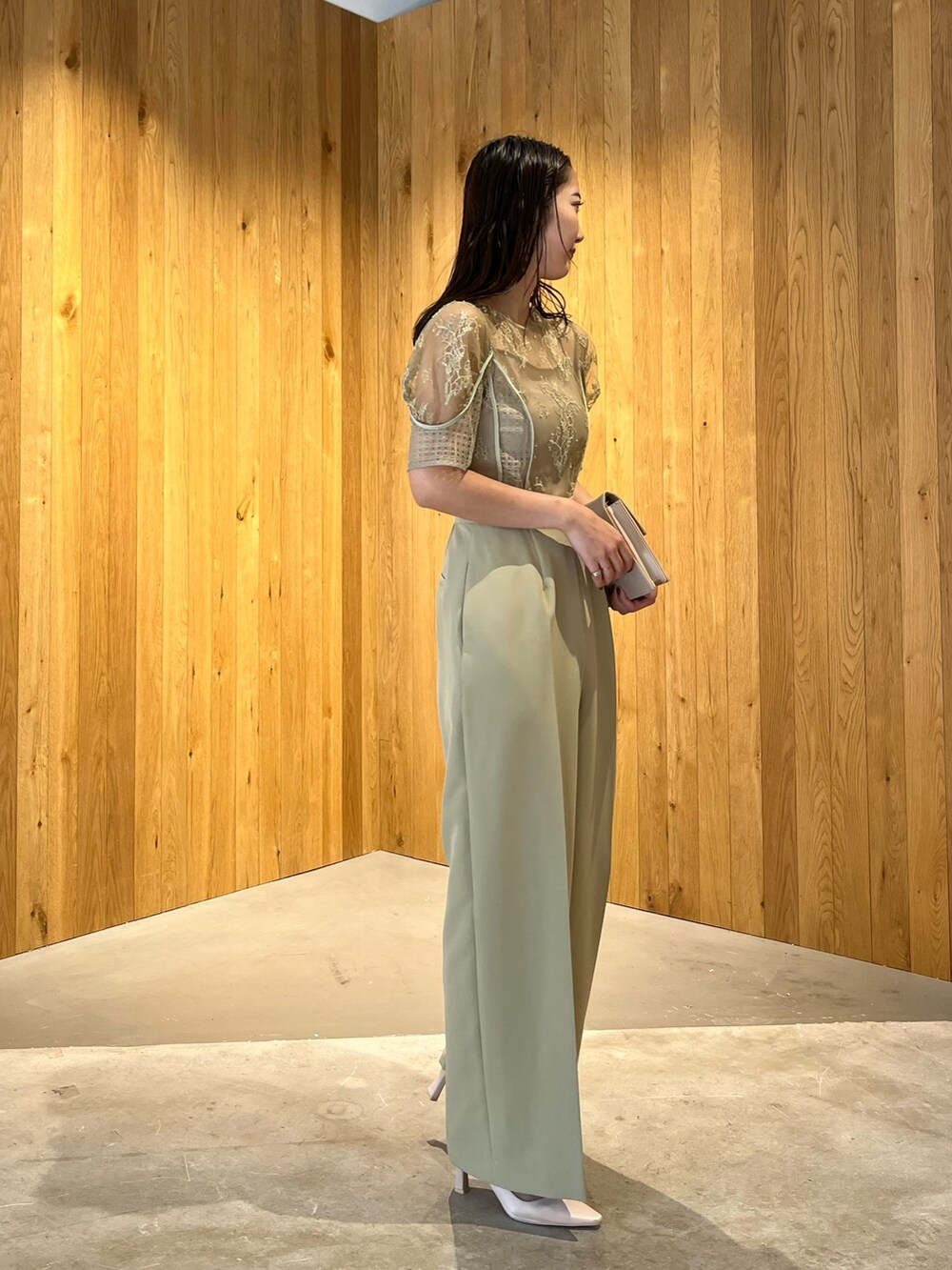 ベージュ系のパンプス、ベージュ系のクラッチバッグ、グリーン系のパンツドレスを着用したレディースの冬コーディネートの3枚目の写真