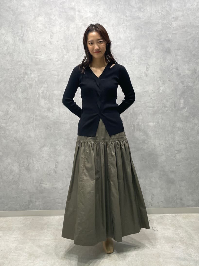 ベージュ系のスカート、ベージュ系のブーツ、ブラック系のニット/セーターを着用したレディースの秋コーディネートの2枚目の写真