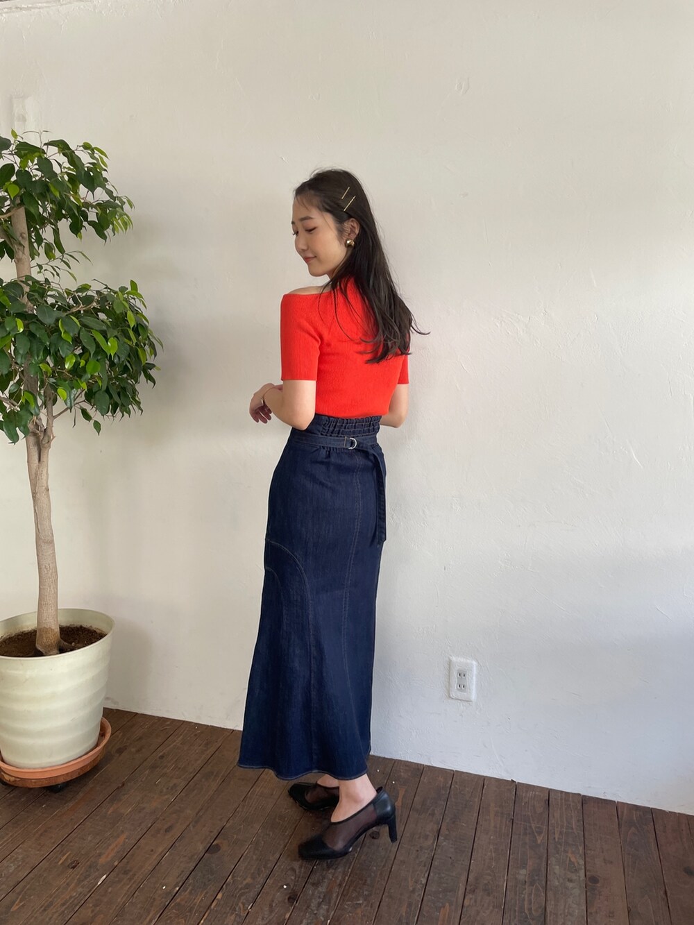 オレンジ系のニット/セーター、ブルー系のデニムスカート、ブラック系のパンプスを着用したレディースの春コーディネートの3枚目の写真