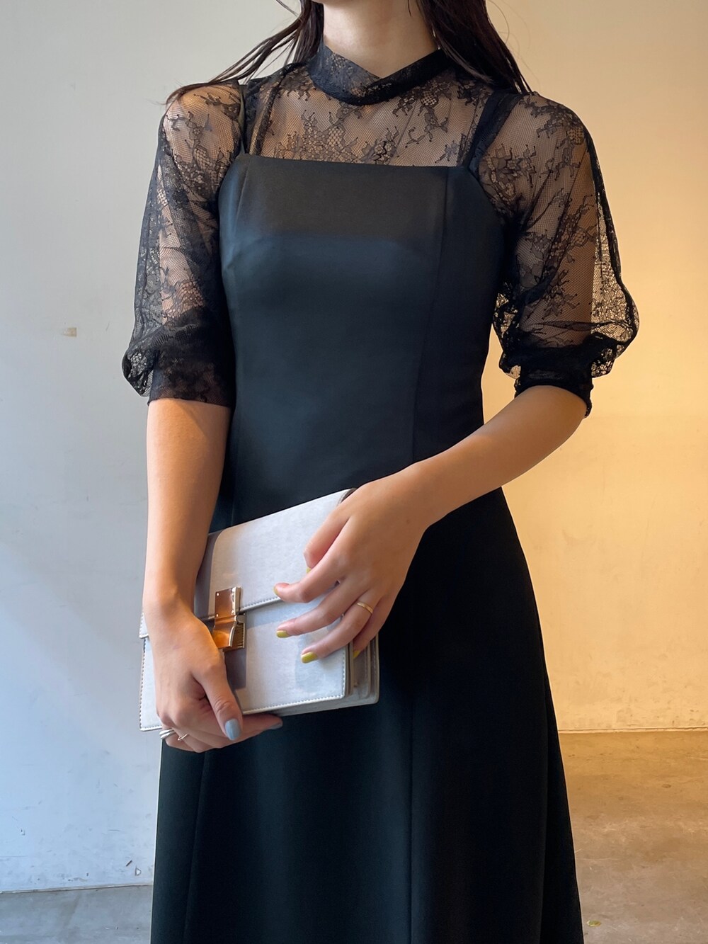 グレー系のパンプス、ブラック系のドレス、グレー系のクラッチバッグを着用したレディースの冬コーディネートの9枚目の写真