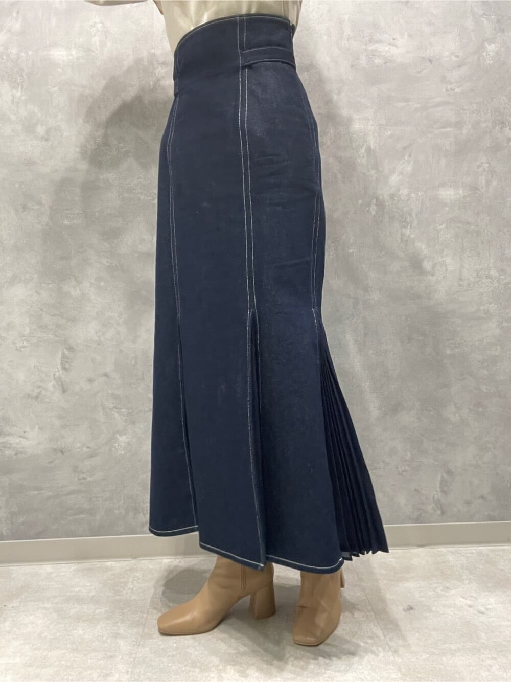 ベージュ系のブーツ、ブルー系のスカート、ホワイト系のニット/セーターを着用したレディースの秋コーディネートの9枚目の写真