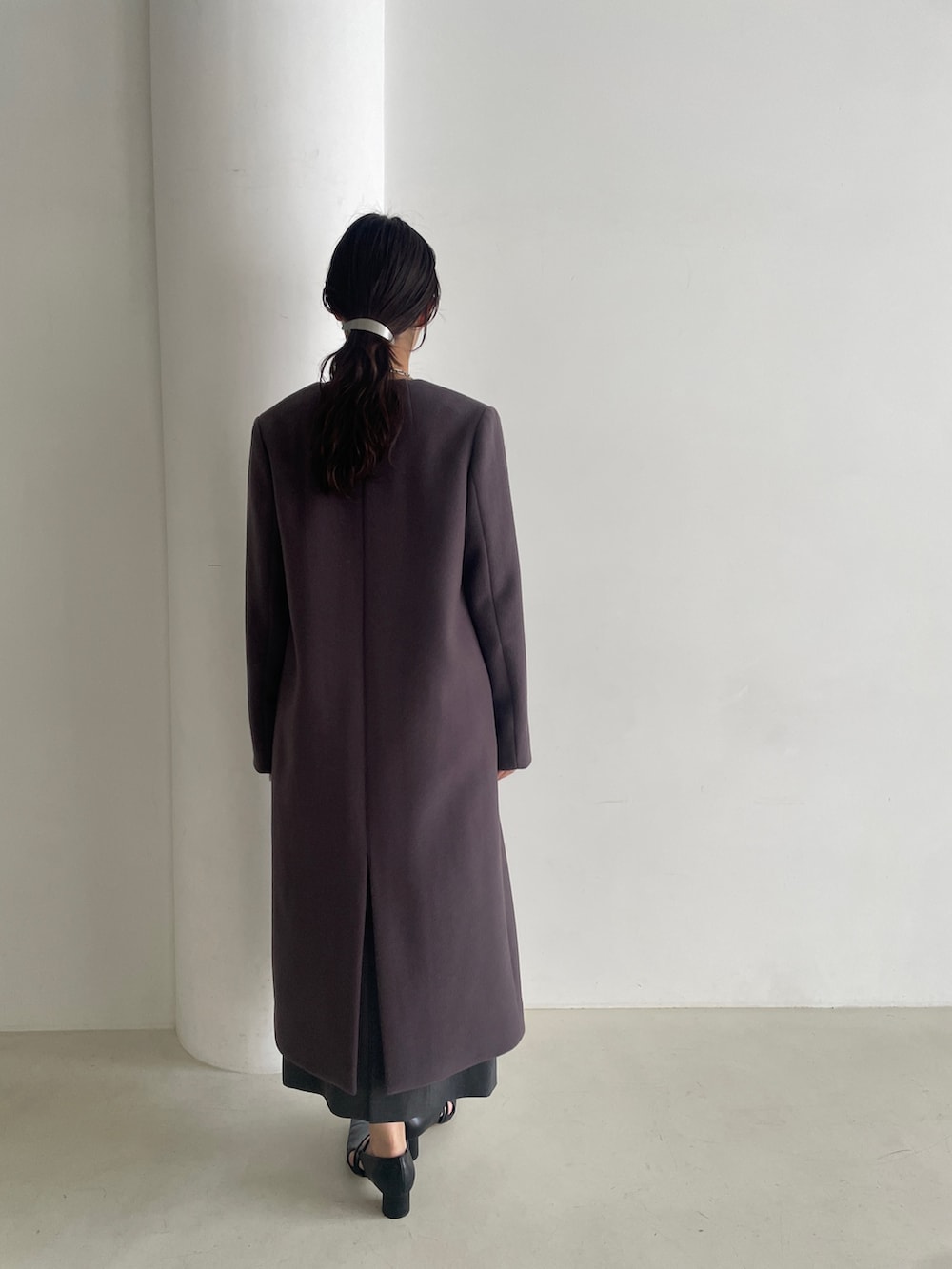 グレー系のドレス、ブラック系のパンプス、グレー系のチェスターコートを着用したレディースの秋コーディネートの6枚目の写真