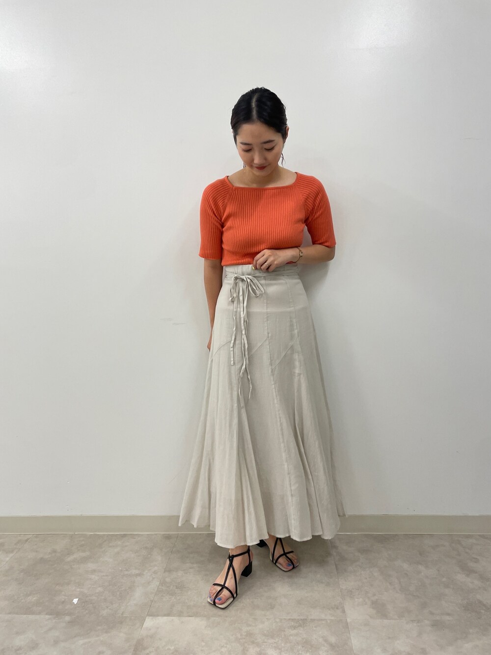 グレー系のスカート、ピンク系のニット/セーター、ブラック系のサンダルを着用したレディースの夏コーディネートの2枚目の写真