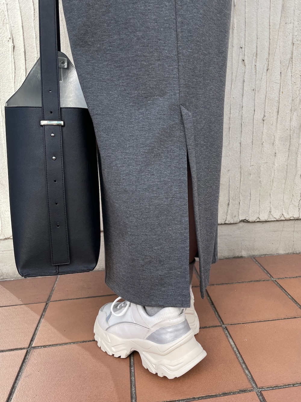 ブラック系のショルダーバッグ、グレー系のワンピース、ホワイト系のスニーカーを着用したレディースの冬コーディネートの7枚目の写真