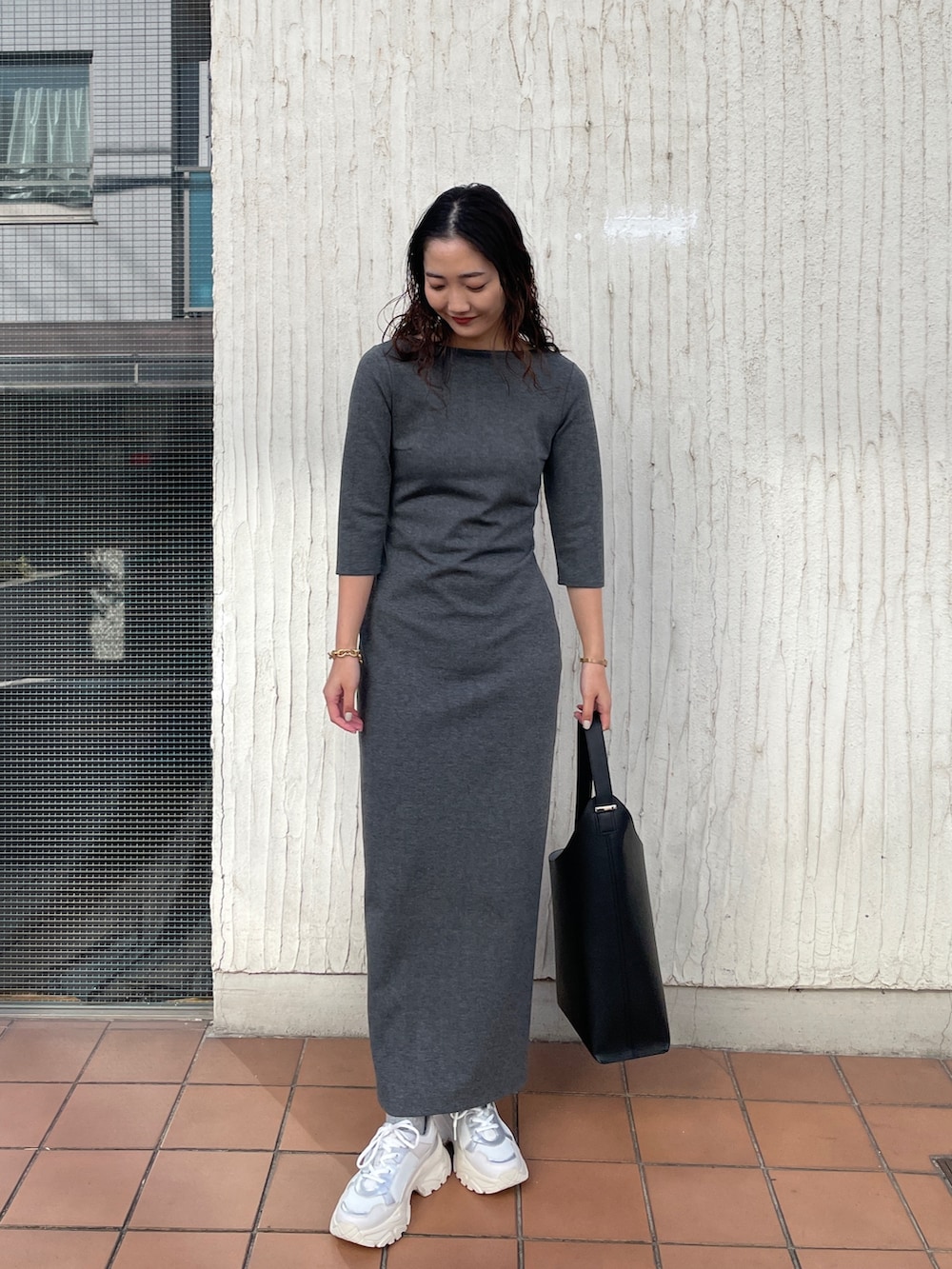 ブラック系のショルダーバッグ、グレー系のワンピース、ホワイト系のスニーカーを着用したレディースの冬コーディネートの2枚目の写真