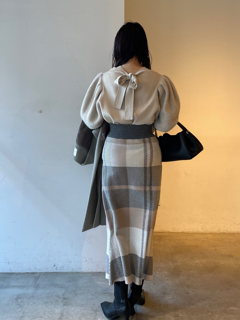 ブラック系のブーツ、ベージュ系のスカート、ホワイト系のニット/セーターを着用したレディースの冬コーディネートの4枚目の写真