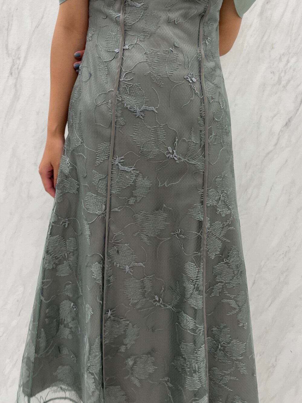 ホワイト系のパンプス、グリーン系のドレスを着用したレディースの冬コーディネートの8枚目の写真