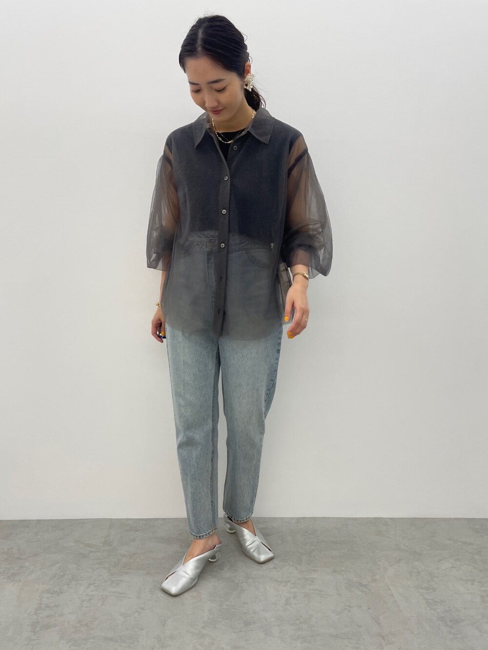 ブルー系のデニムパンツ、シルバー系のパンプス、ブラック系のニット/セーターを着用したレディースの夏コーディネートの2枚目の写真