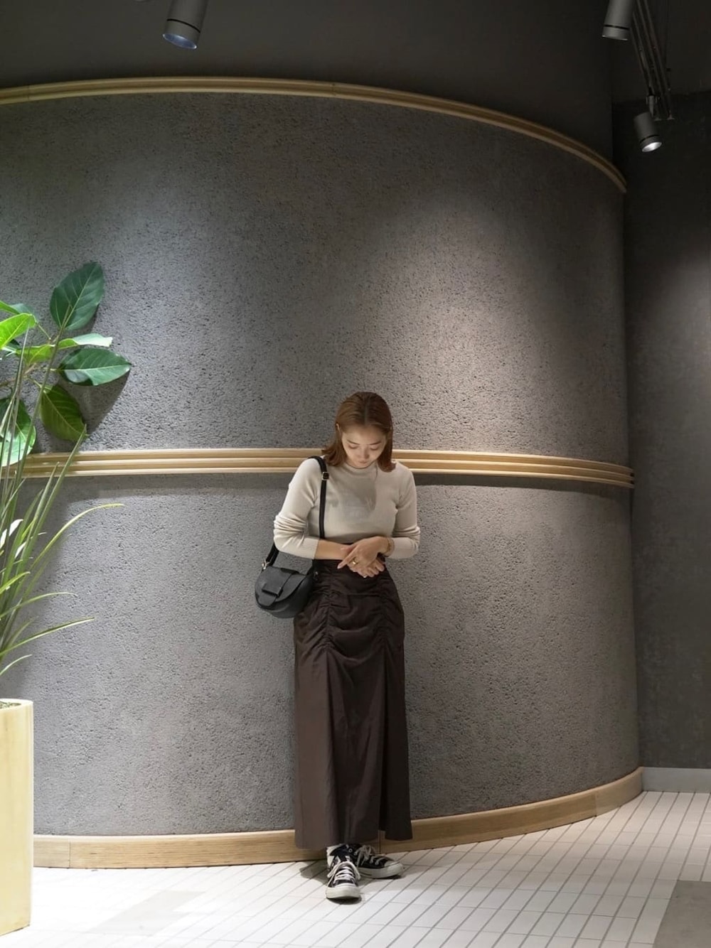 ブラック系のショルダーバッグ、ブラウン系のスカート、ホワイト系のニット/セーターを着用したレディースの秋コーディネートの2枚目の写真