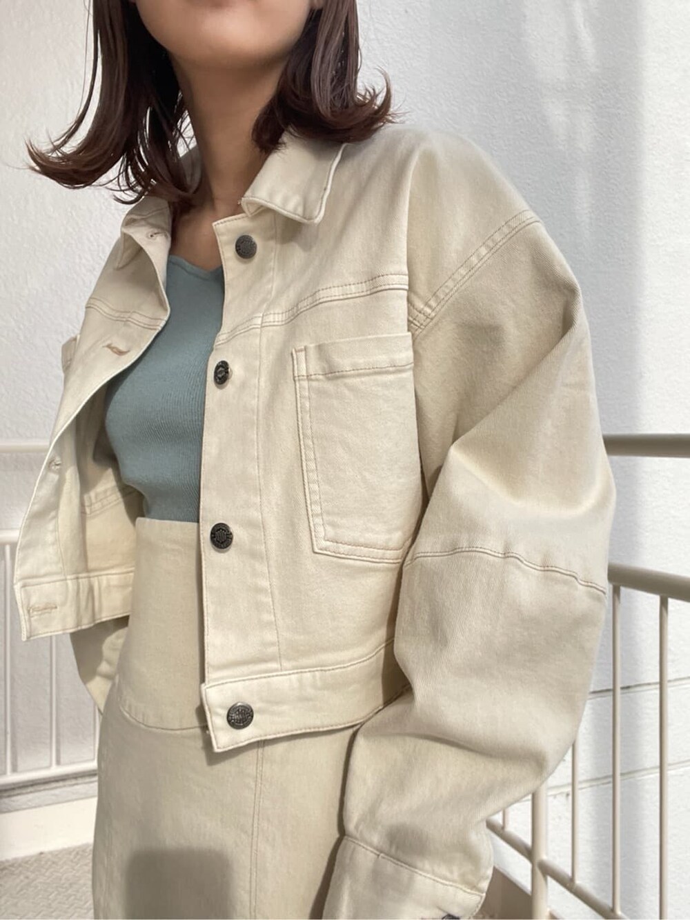 ホワイト系のブルゾン、ホワイト系のスカート、ホワイト系のパンプスを着用したレディースの冬コーディネートの2枚目の写真