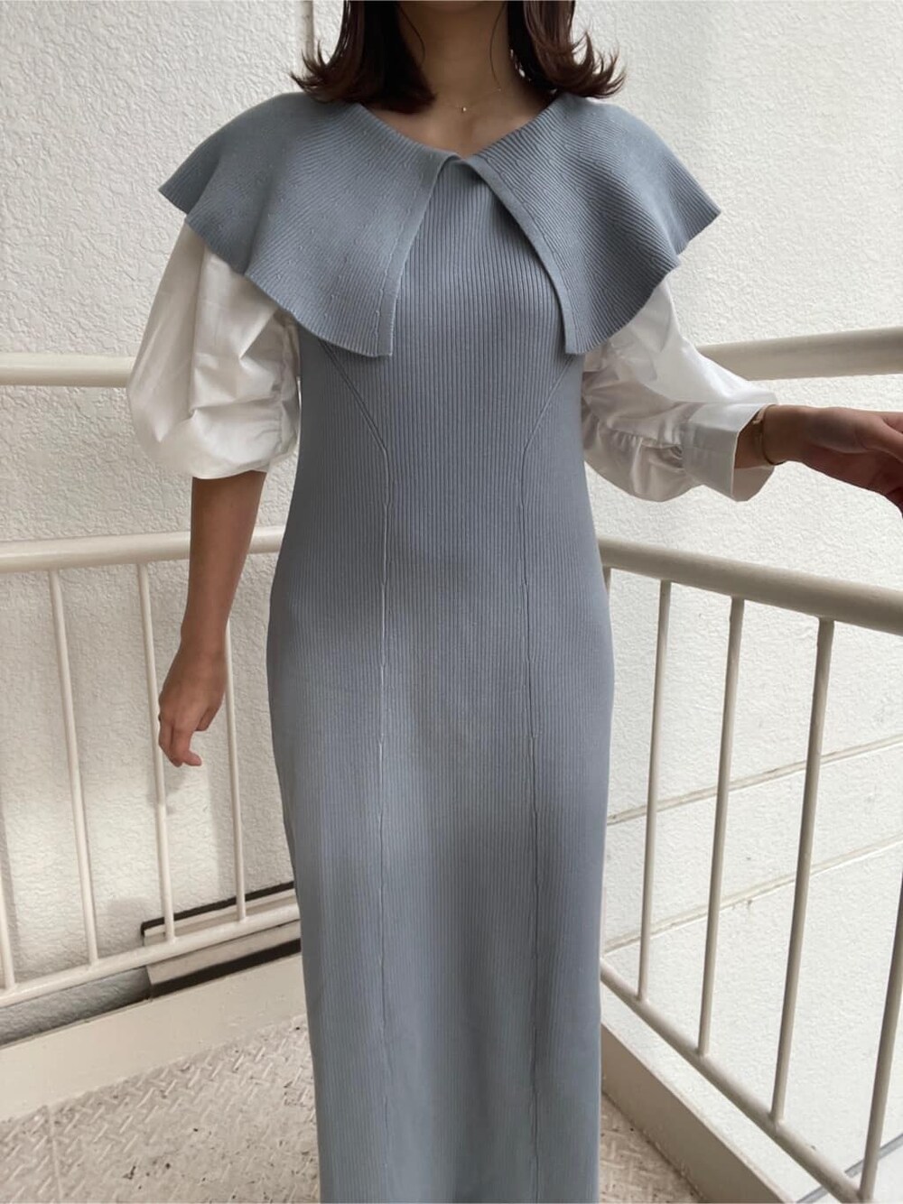 ブルー系のワンピース、ブラック系のハンドバッグ、ホワイト系のパンプスを着用したレディースの冬コーディネートの7枚目の写真