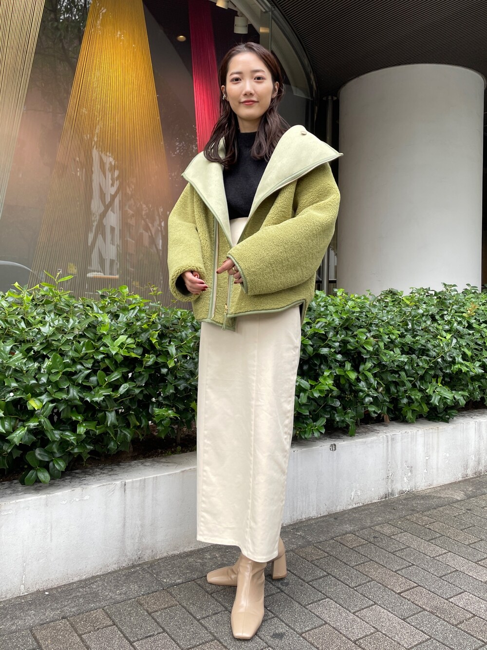 ベージュ系のブーツ、ブラック系のニット/セーター、ホワイト系のスカートを着用したレディースの秋コーディネートの3枚目の写真