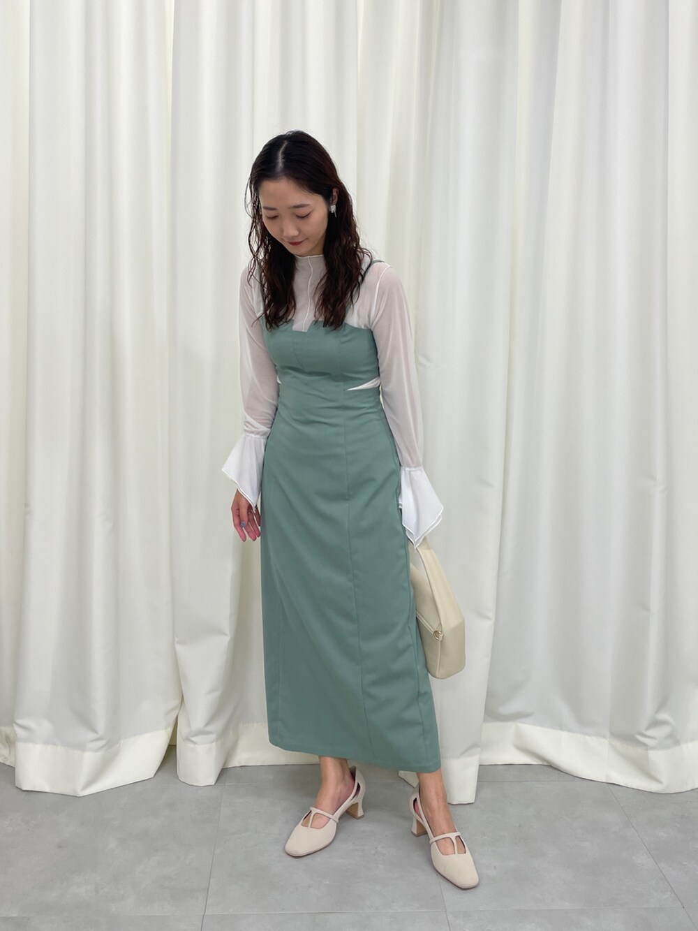 グリーン系のワンピース、ホワイト系のパンプスを着用したレディースの春コーディネートの2枚目の写真